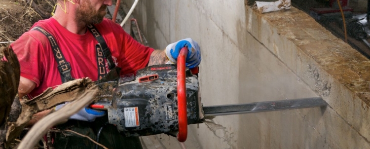 Cut egress window hole in basement wall with hydraulic powered concrete chain saw